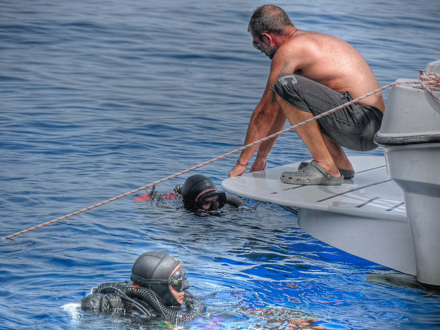 Captain Mihalis Kelaidis helping Evan Kovacs & Brett Seymour back into the boat after their dive.